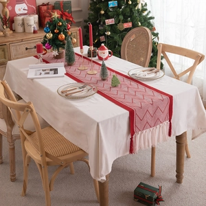 Red Christmas table runner with white geometric V-pattern and tassels in festive setting