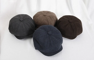 Dettaglio di berretti newsboy in tweed a spina di pesce nei colori grigio, caffè e blu navy