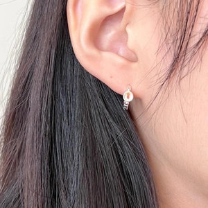 Close-up of a minimalist 925 sterling silver hoop earring with a small strawberry crystal charm