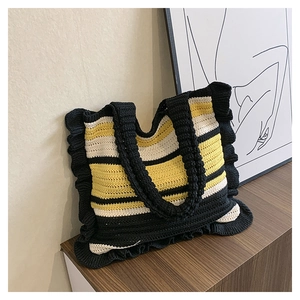 Detail of handmade knit tote bag with black, white, yellow stripes and ruffled edges