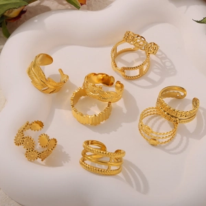 Minimalistisches Set aus goldenen Ringen mit Feder und Flechtstruktur in weißer Schale