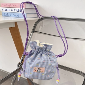 Detail of purple plaid drawstring bucket bag with cute patch and beaded rope strap
