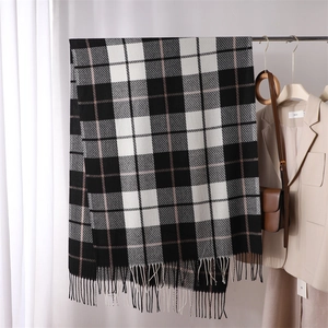 Detail of pink and black plaid scarf featuring soft fringe trim and cashmere-like texture