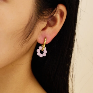 Detailaufnahme von Model mit rosa Blumen-Perlenohrringen in Gold bei sanftem Licht