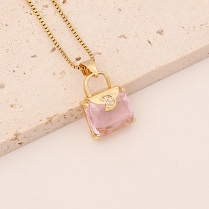 Detail shot of a golden handbag pendant necklace with a pink square crystal and zircon