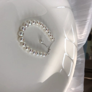 Macro shot of high-luster white pearls in a ceramic bowl with an adjustable silver chain