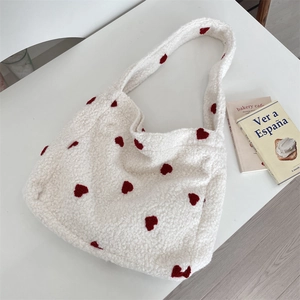 Detail shot of the white plush tote bag texture with red heart pattern and soft fabric