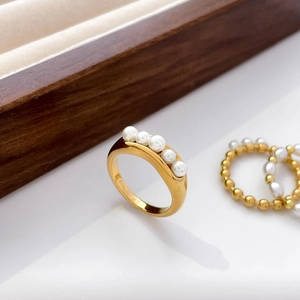 Macro detail of gold-plated pea pod ring with freshwater pearls and crossed lines design