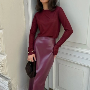Dettaglio della gonna a vita alta in ecopelle bordeaux con spacco laterale e vestibilità slim
