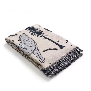 Close-up of bohemian woven camping blanket with wolf pattern and fringed edges