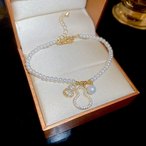 Bracelet en perles avec doubles pendentifs gourde et cristaux dans son écrin orange