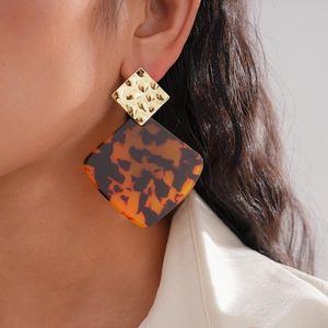 Detail of amber tortoiseshell geometric drop earrings with hammered gold finish