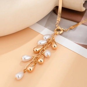 Close-up of golden fringe necklace with faux pearls on a smooth snake chain detail