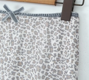 Detailansicht von Leopardenmuster-Stoff mit grauer Wildlederschleife und Netzstruktur