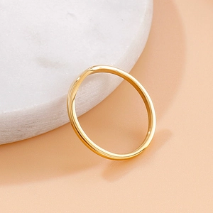 Minimalist gold titanium steel ring with a subtle V-shaped curve on marble stand