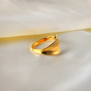 Detail eines 18K vergoldeten offenen Rings auf elegantem weißem Seidenstoff