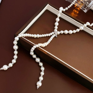 Detail of long pearl sweater necklace with diamond-set heart buckle and gradient beads