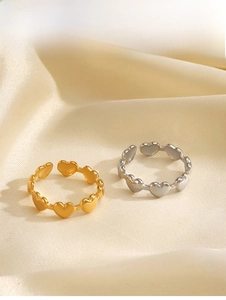 Close-up of gold and silver heart-shaped link rings on soft beige silk fabric