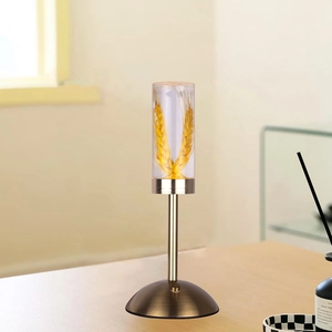 Detail of golden table lamp with wheat stalks encased in transparent acrylic lampshade