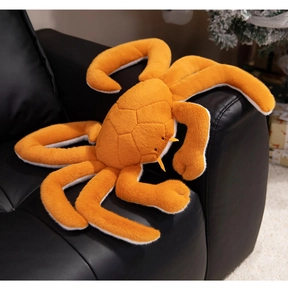 Detail of orange plush crab toy with diamond pattern stitching on a black sofa