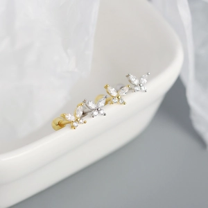 Macro shot of butterfly stud earrings in gold and silver with sparkling zircon stones