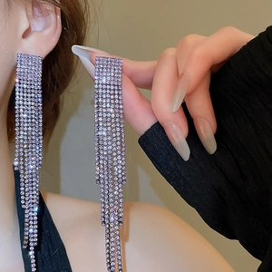 Close-up of dangling silver tassel earrings with purple diamonds and fringe details