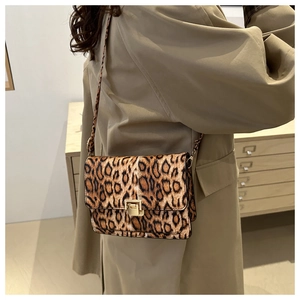 Detail of leopard print PU leather shoulder bag with gold metal buckle on khaki trench coat