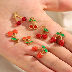 DIY cherry pendants in red and 18K gold finish held in palm for jewelry making