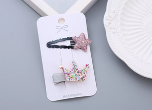 Glittering star and crown hair clips for girls set on white card with handmade label