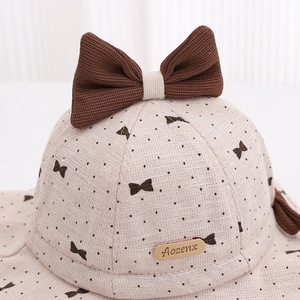 Beige baby bucket hat with large brown knit bow and polka dot floral pattern