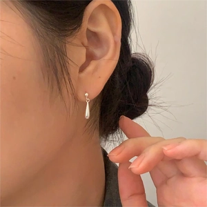Primo piano di orecchini a goccia in argento indossati da una modella in stile chic