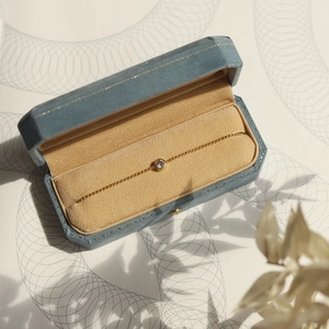 Bracelet à billes dorées minimaliste avec diamant rond dans un écrin en velours bleu