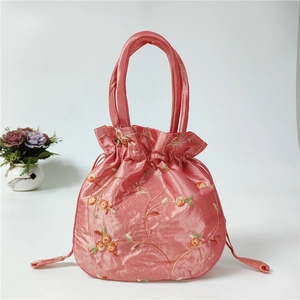 Detail of pink embroidered silk handbag with floral patterns and drawstring closure