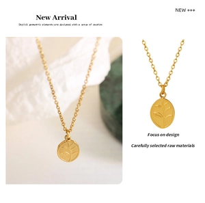 Detailed view of an oval gold-plated pendant with embossed leaf patterns on a fine chain
