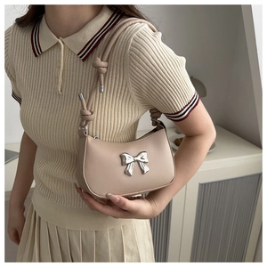 Close-up of beige PU leather shoulder bag with silver bow accent and knotted strap detail