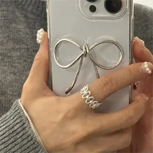 Detailed view of an elegant hollow chain link silver ring on a model holding a phone case