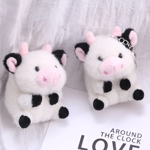 Detalle de llaveros de peluche de vaca con pelo suave blanco y manchas negras decorativas
