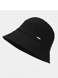 Detail of summer bucket hat with wavy pleat texture and elegant silver metal tag accent
