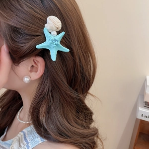 Detail of starfish and shell hair clips with pearls on wavy brown hair for vacation