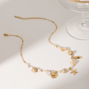 Detail of gold starfish and shell pendants with beads on a delicate beach necklace