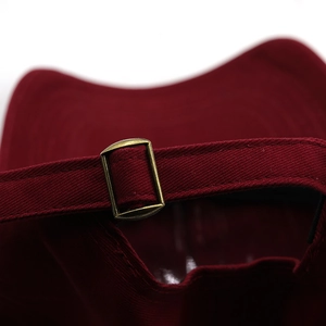 Detail of red cotton baseball cap featuring adjustable bronze metal buckle at the back