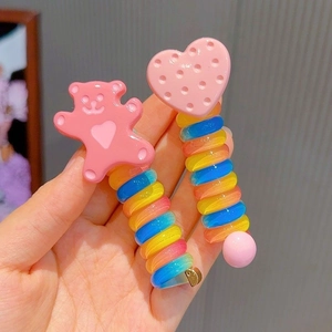 Close-up of rainbow spiral hair ties featuring cute pink bear and heart cookie charms