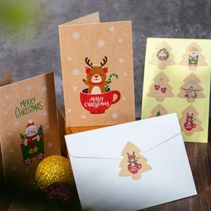 Christmas kraft paper greeting cards set with cartoon stickers and white envelope on wood