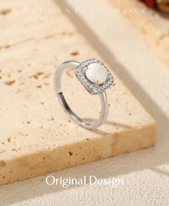 Macro shot of silver ring with square opal stone and diamond halo on stone texture