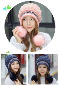 Dettaglio di caldi berretti in maglia con paraorecchie e doppi pompon in rosa e blu scuro