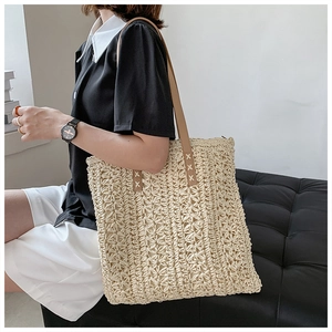Close-up of woven tote bag with diamond texture and brown leather shoulder straps