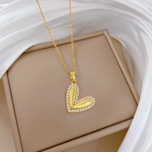 Close-up of a gold heart necklace with crystals on a beige jewelry box and silk