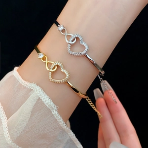 Macro shot of gold and silver heart bracelets with infinity symbols on a wrist
