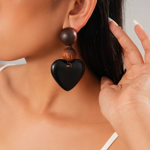Close-up of three-tier statement earring with brown wood beads and black heart pendant