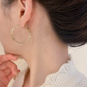 Close-up of vintage golden twist hoop earrings with intricate braided texture design